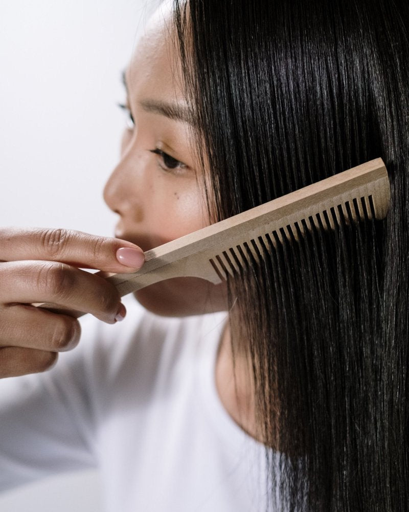 Comb gliding through smooth, glossy dark hair