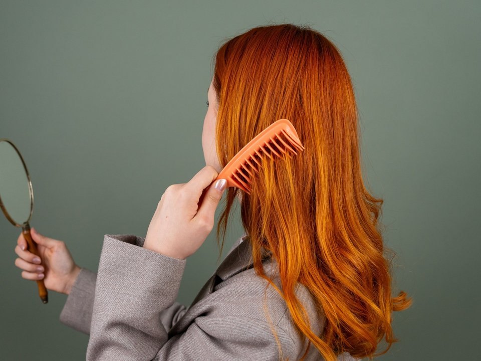 Woman combing her copper-colored hair