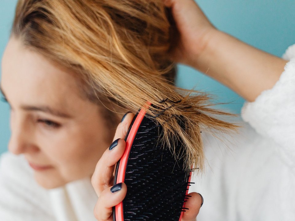 Woman brushing through tangled, dry hair